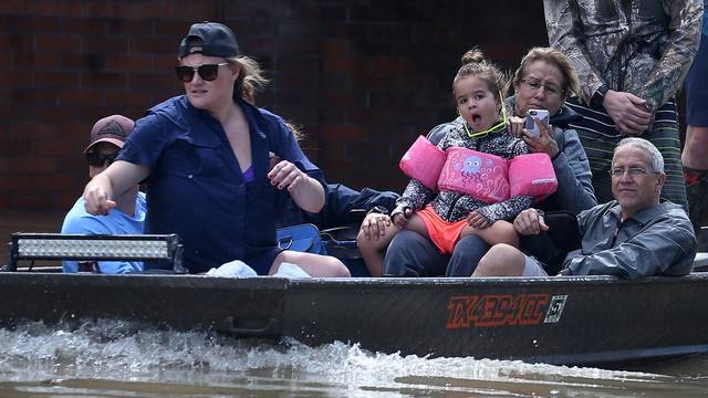 People ride a boat though flood water after being evacuated from the rising water following Hurricane Harvey in a neighborhood west of Houston, Texas