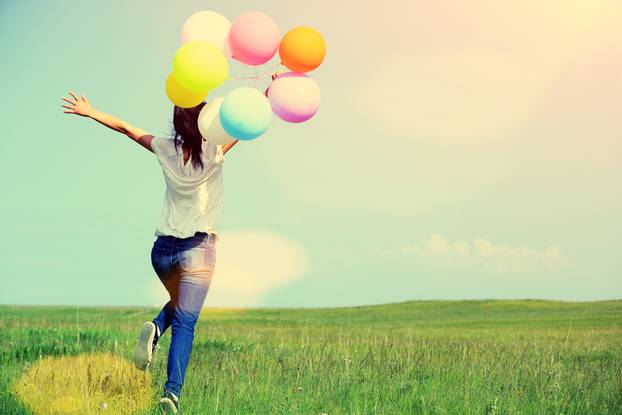 young asian woman running and jumping with colored balloons