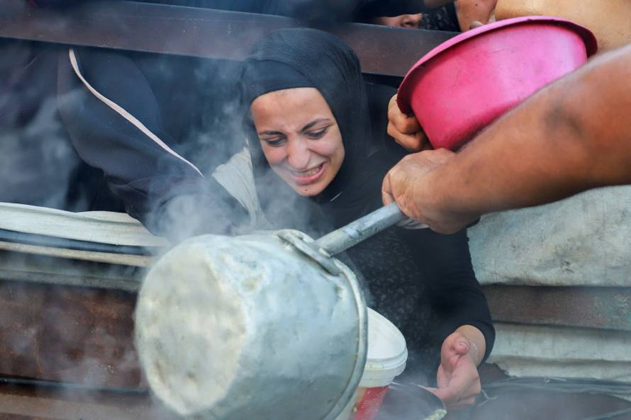Palestinians wait to receive food from a charity kitchen amid hunger crisis, in Gaza City