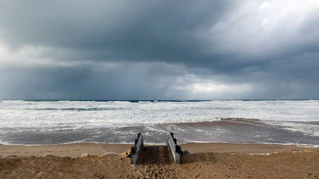 Clouds hang in the sky above the Atlantic ocean as waves from an early winter storm covers the beachfront in Lacanau