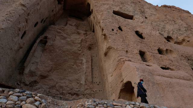 FILE PHOTO: A Taliban soldier stands guard in front of the ruins of a 1500-year-old Buddha statue in Bamyan