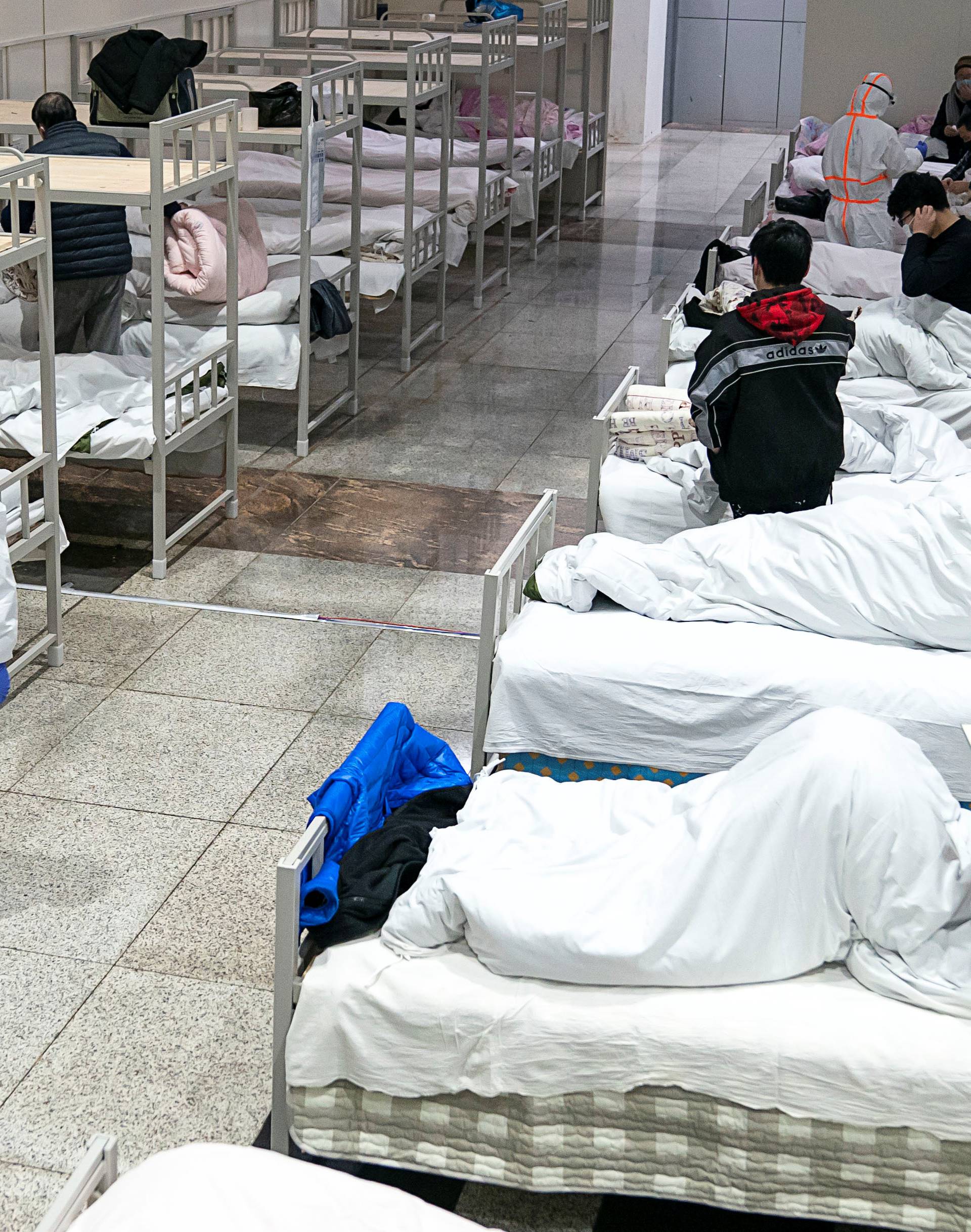 Medical workers in protective suits attend to patients at the Wuhan International Conference and Exhibition Center