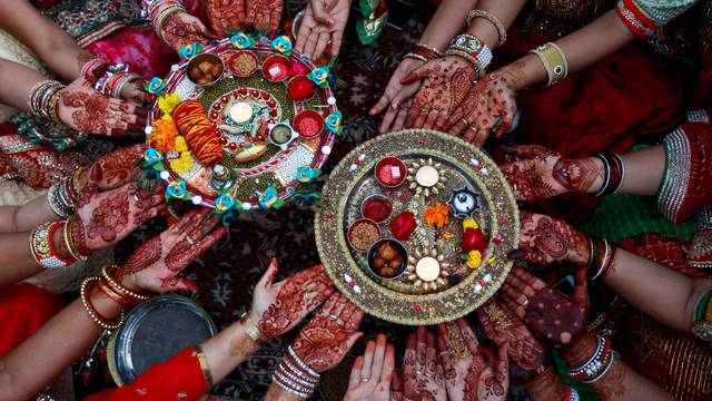 Married women pose for pictures as they perform rituals for the well being of their husbands during the Hindu festival of Karva Chauth in Ahmedabad
