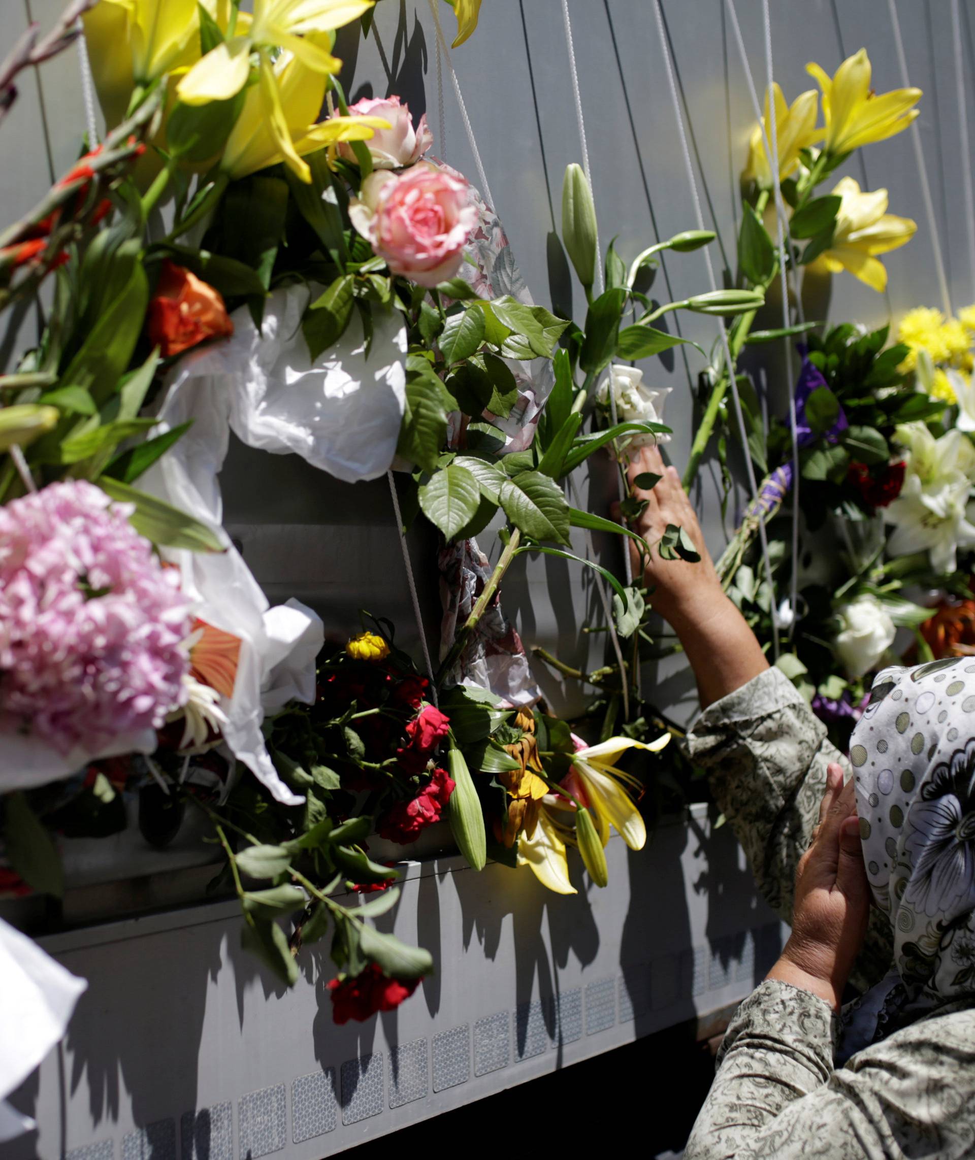 Women place flowers on a truck carrying coffins of newly identified victims of the 1995 Srebrenica massacre, in front of the presidential building in Sarajevo