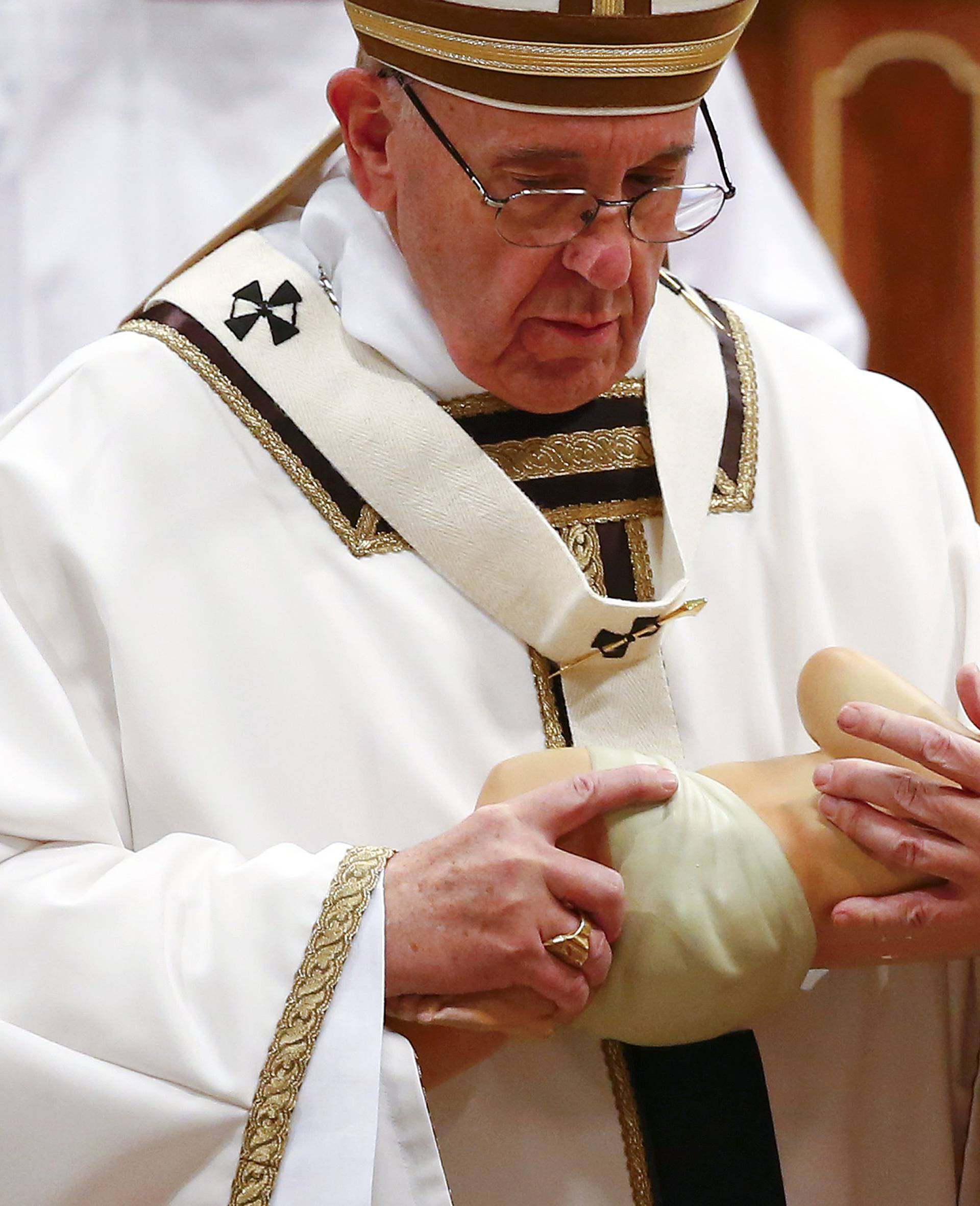 Pope Francis holds a statue of baby Jesus during the Christmas night Mass in Saint Peter's Basilica at the Vatican