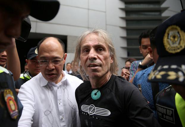 French climber Robert is escorted by Filipino cops after his 47-storey GT International Tower climb in Makati City
