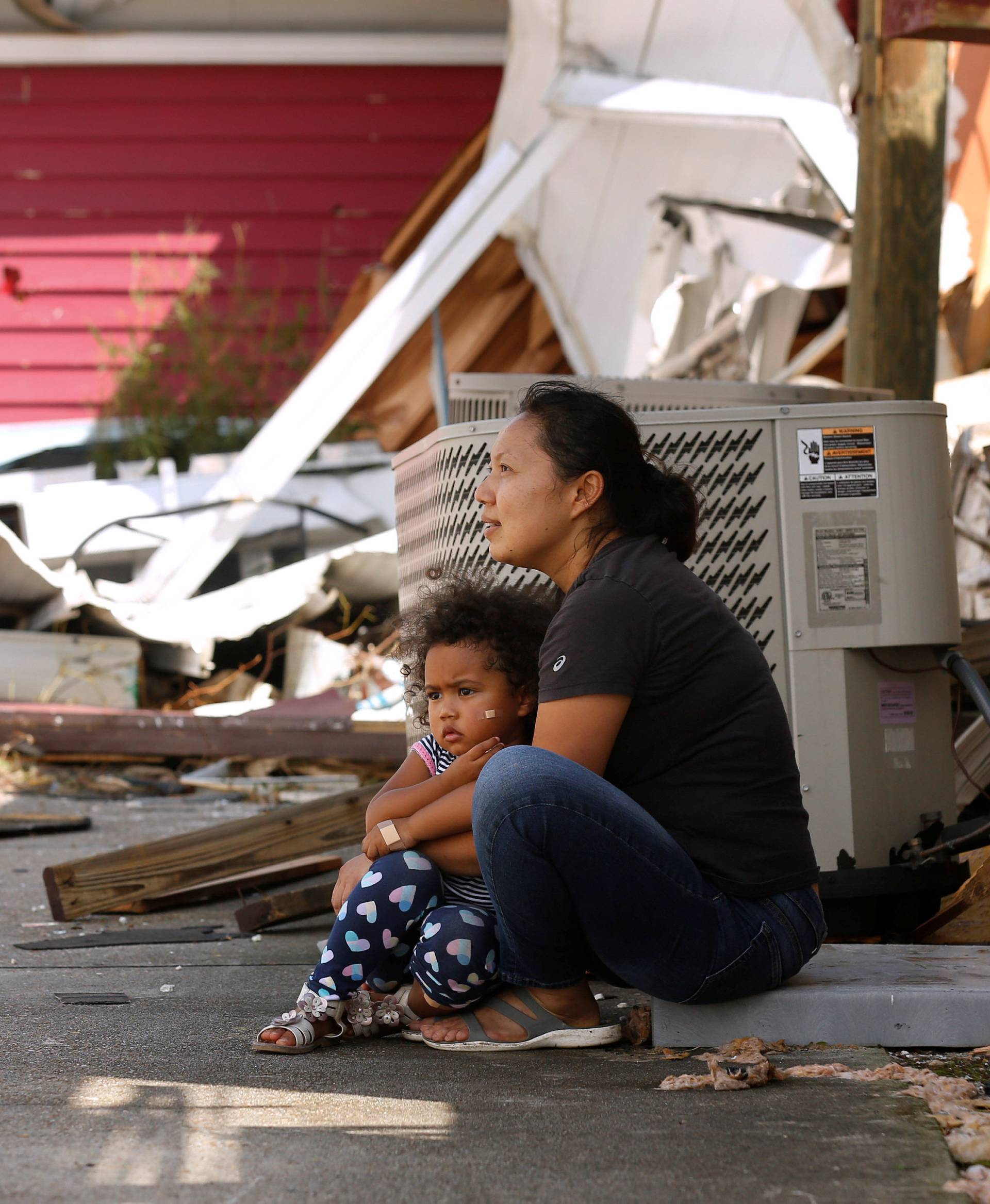 Wimlin Washington and her 3-year-old daughter Mia sit in front of their restaurant, damaged by Hurricane Michael in Callaway