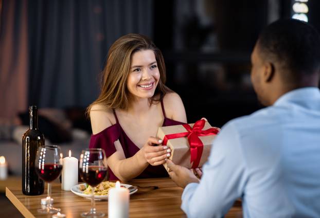 Happy Woman Getting Gift From Her Black Boyfriend On Dinner At Restaurant