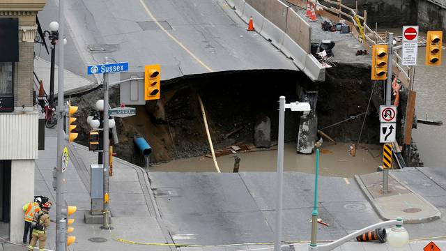Workers look at a large sinkhole in Ottawa