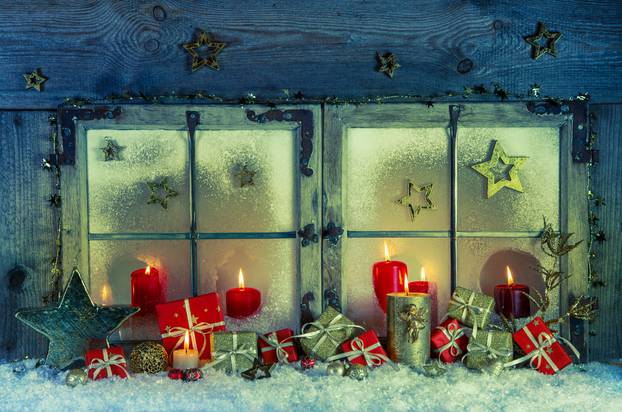 Old wooden window decorated for christmas with red candles and p