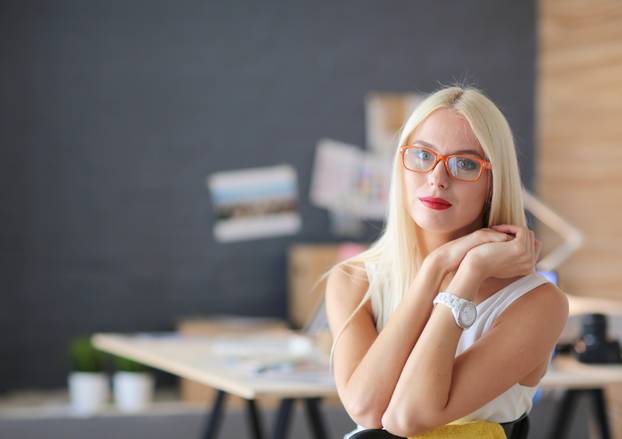 Portrait of an executive professional mature businesswoman sitting on office desk