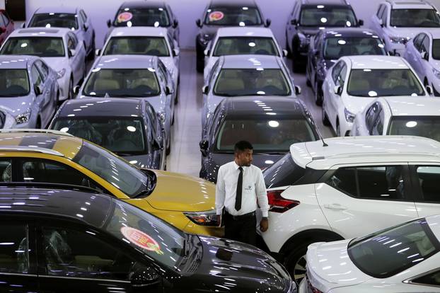 An auto dealer stands between the cars displayed for sale at a second hand car showroom Shoneez Motors in Sanabis, west of Manama