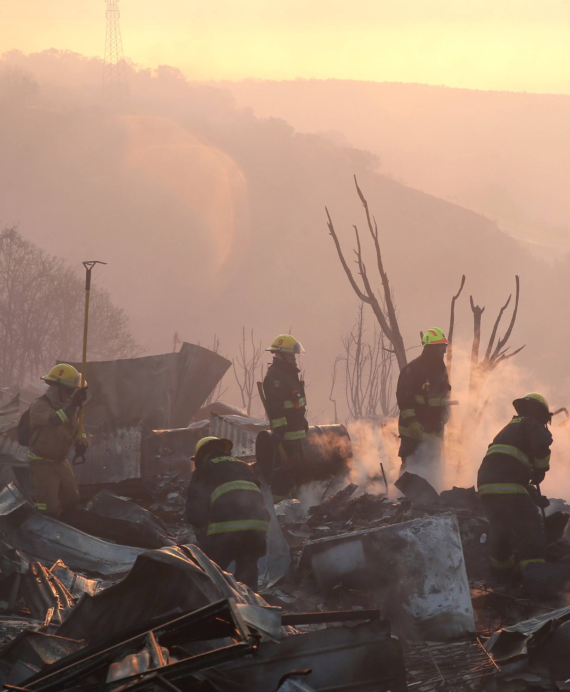 Firefighters remove the remains of a burned house on a hill, where more than 100 homes were burned due to forest fire but there have been no reports of death, local authorities said in Valparaiso, Chile