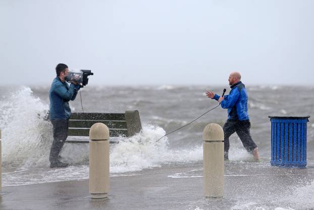 A news crew films as storm surge pushes water from Lake Pontchartrain over Lakeshore Drive