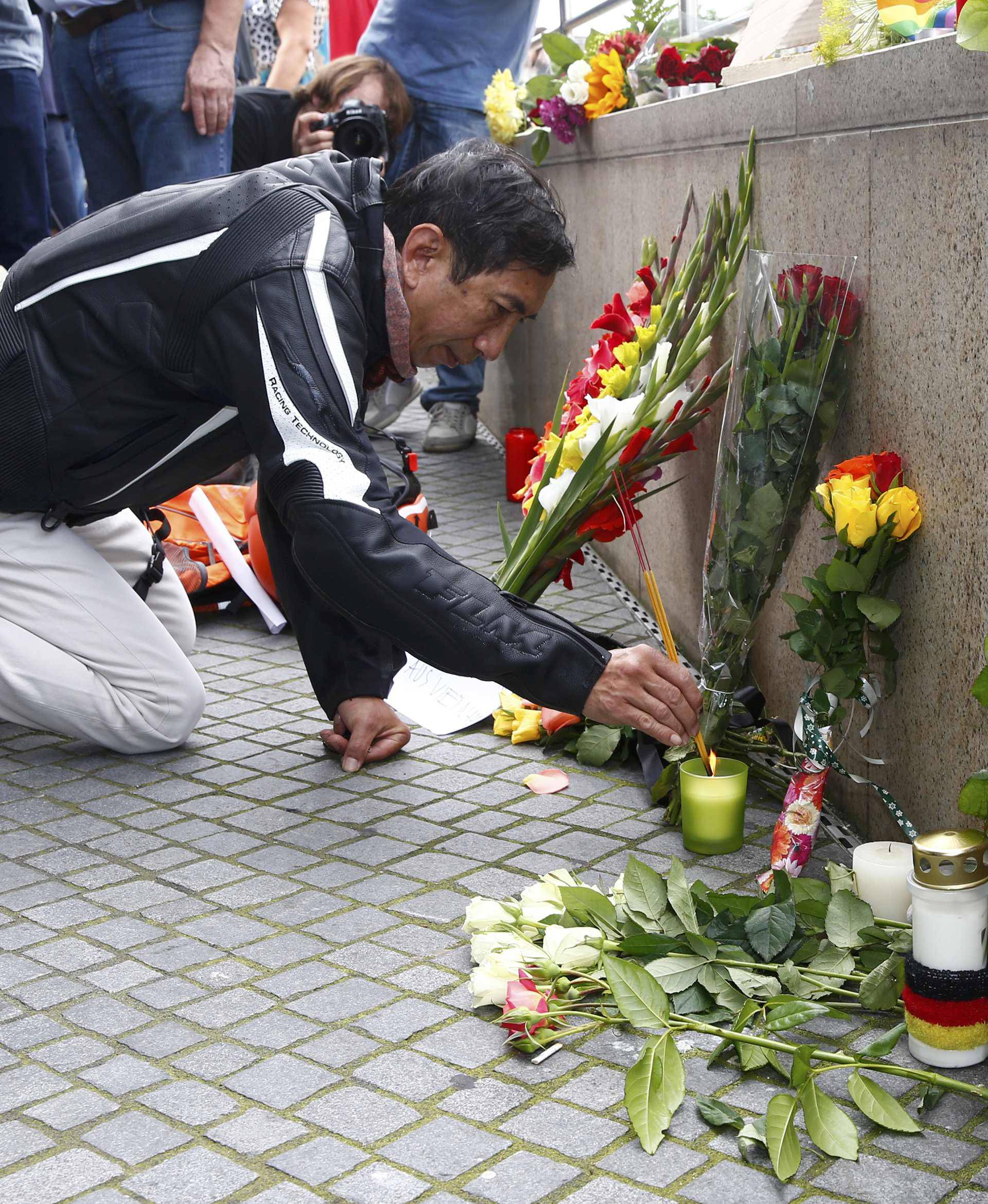 A man lights incense sticks near Olympia shopping mall in Munich