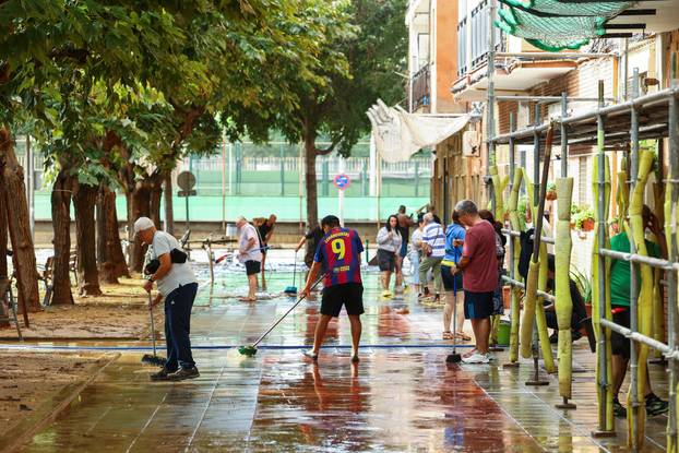 Residents clean a sidewalk in Sant Adria del Besos amid AEMET red alert for Catalonia