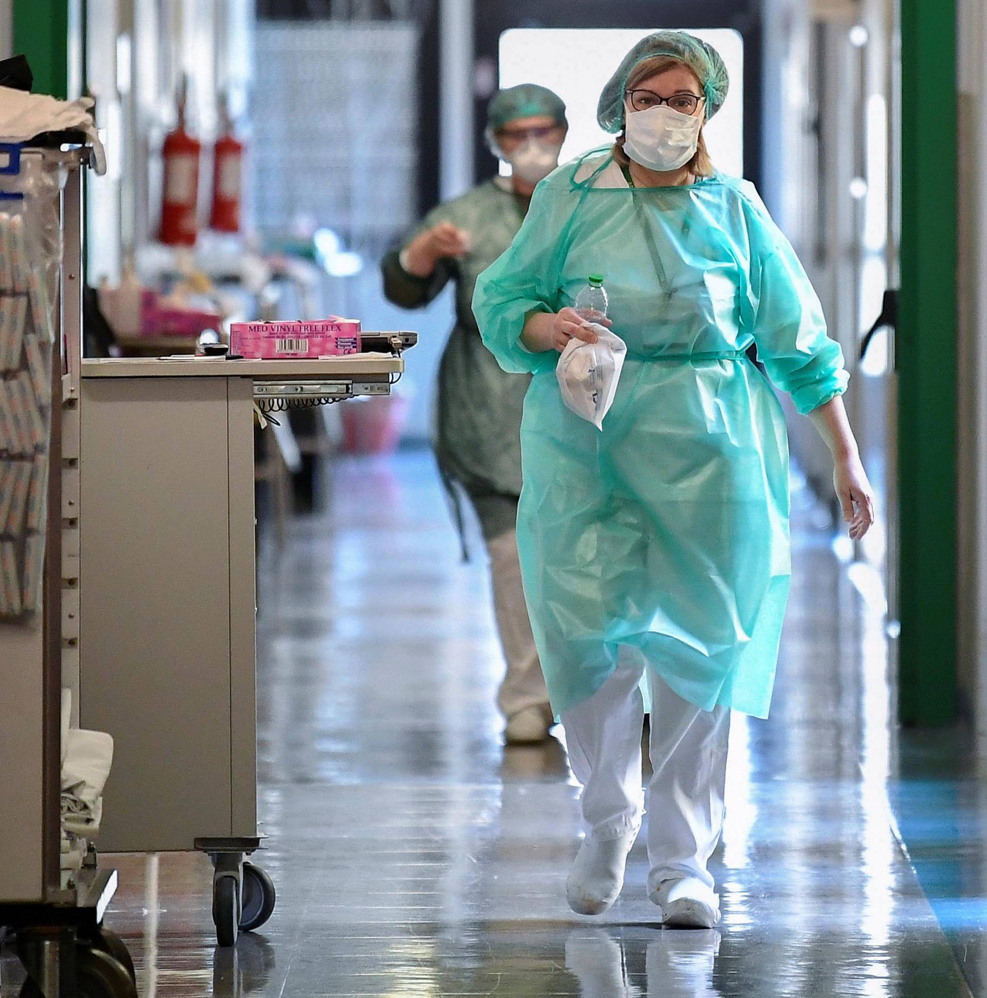 Medical workers wearing protective masks and suits walk in an intensive care unit at the Oglio Po hospital in Cremona