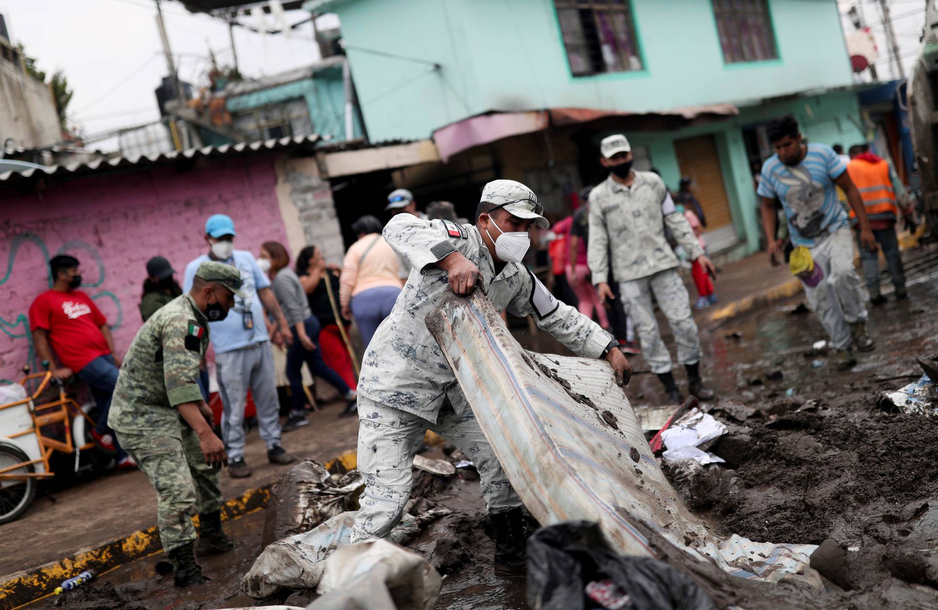 People clean up debris of the damage caused by heavy rainfall in the municipality of Ecatepec