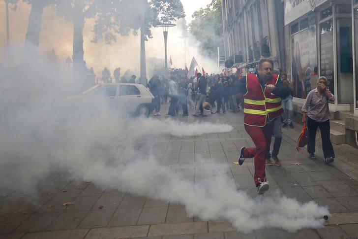 A man runs away from tear gas during clashes with French riot police at a march in Nantes, western France, to demonstrate against the new French labour law