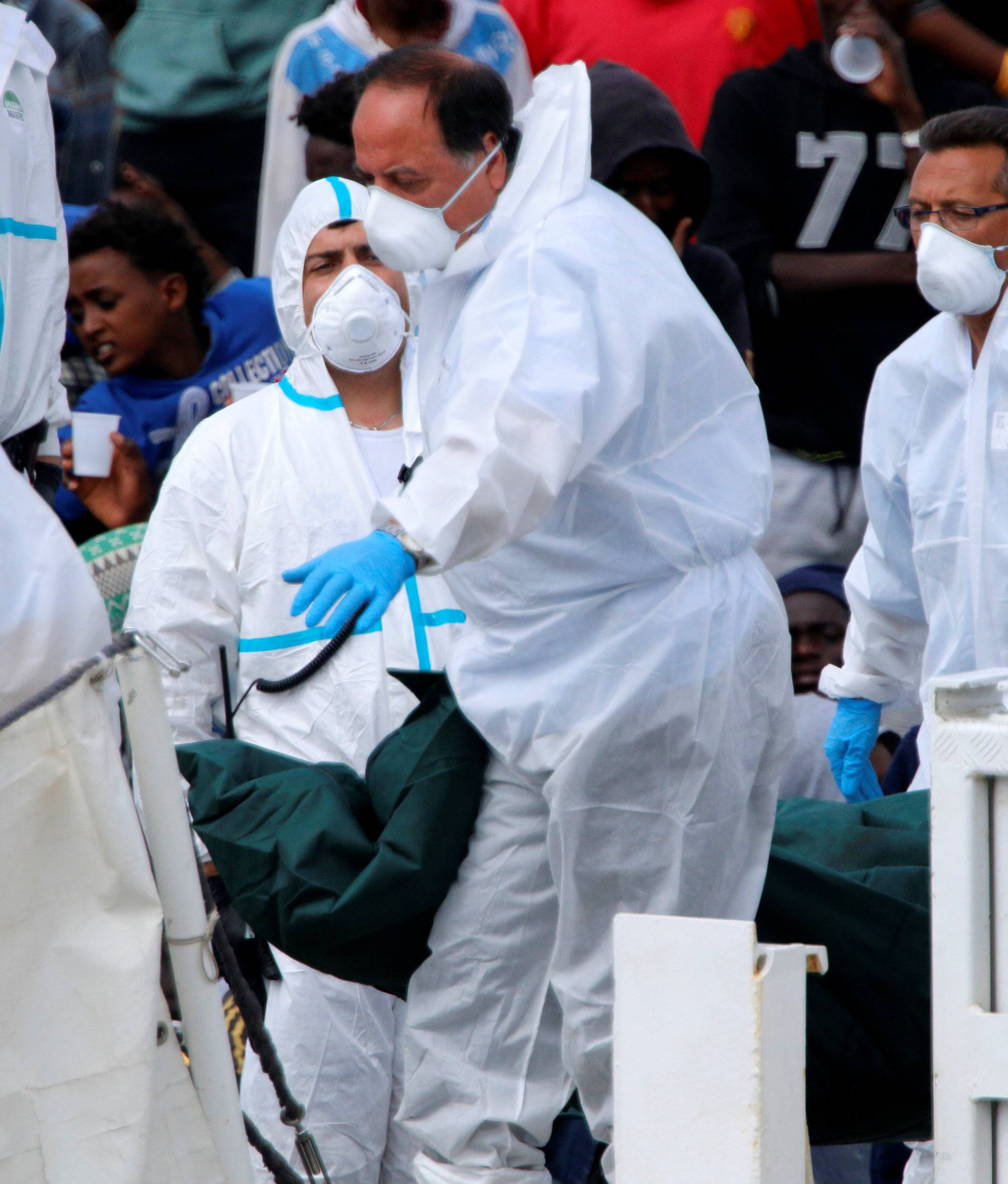 The body of a dead migrant is carried off from the Italian coast guard vessel "Diciotti" at the port of Catania