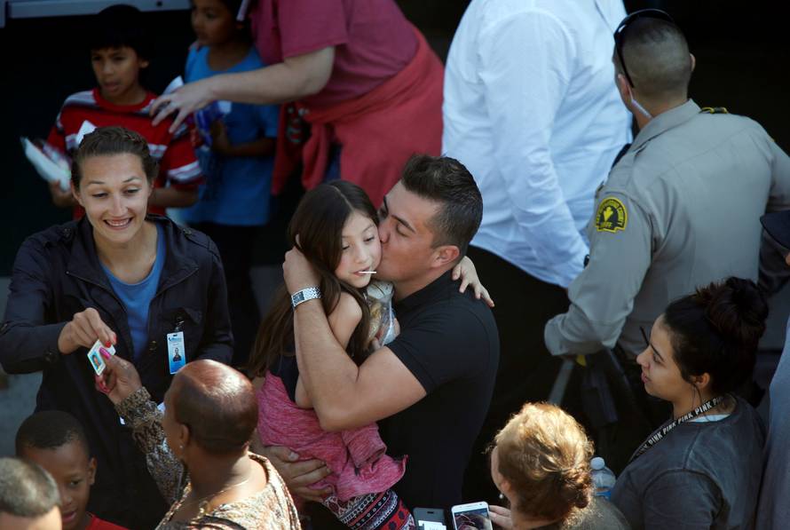 A student who was evacuated after a shooting at North Park Elementary School is embraced after groups of them were reunited with parents waiting at a high school in San Bernardino