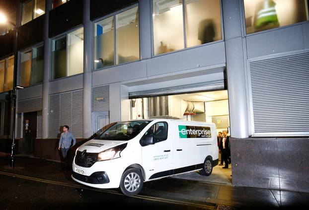 A van and a group of people leave the building which houses the offices of Cambridge Analytica as investigators from Britain