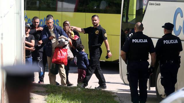 Migrants leave a bus at a camp in Salakovac