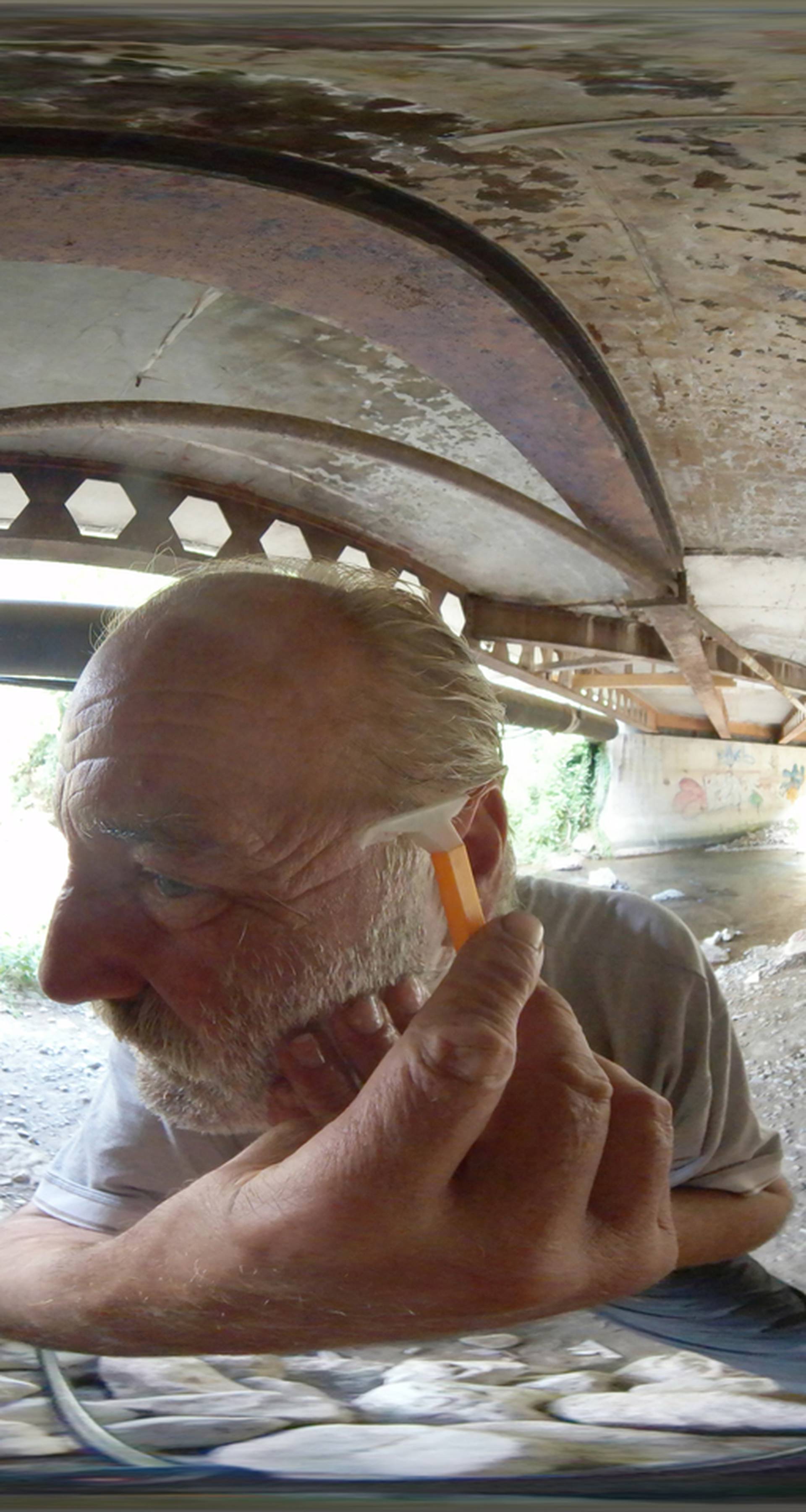 Former steel factory worker Zarko Hrgic shaves under a roadway