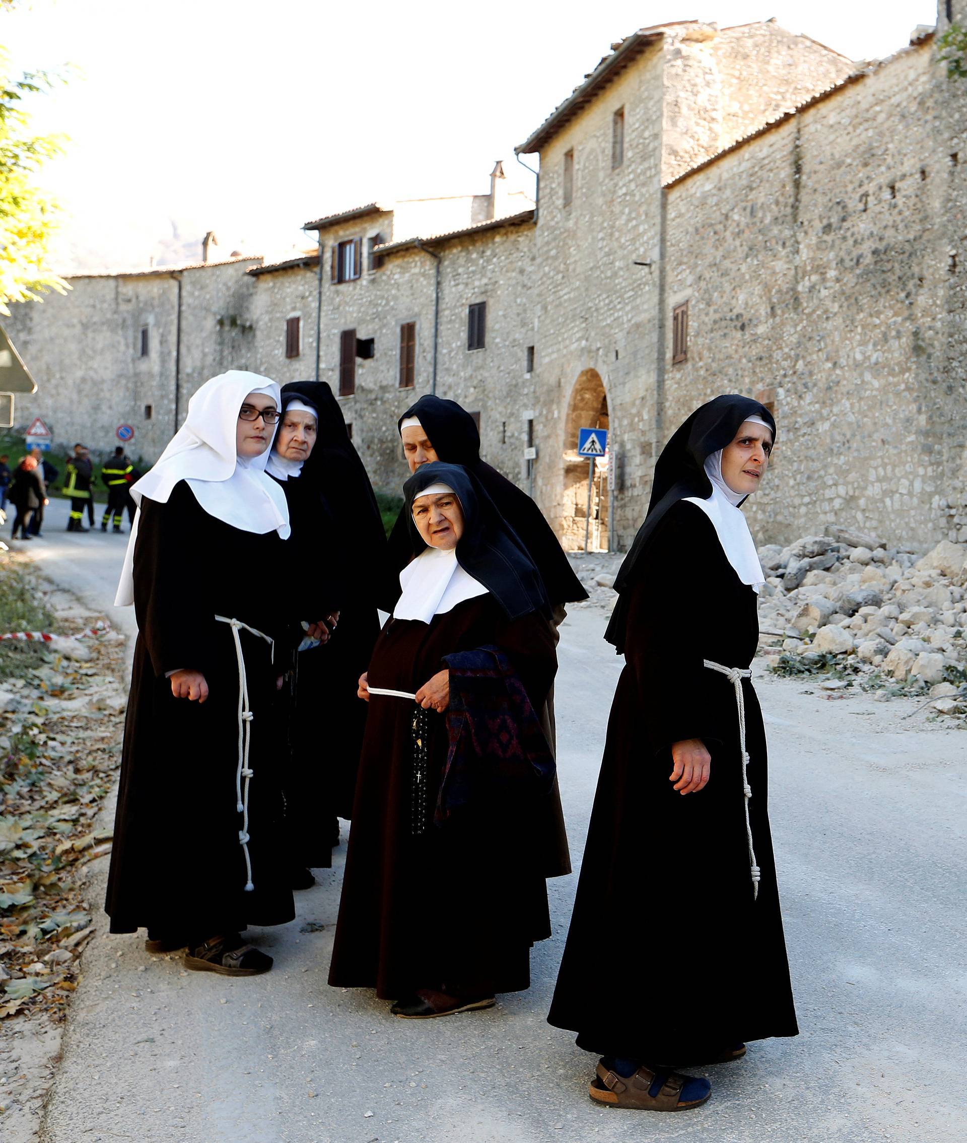 Nuns stand next a partially collapsed wall following an earthquake in Norcia