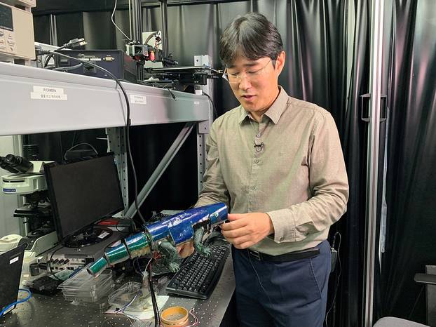 Ko Seung-hwan, mechanical engineering professor at Seoul National University, looks at Chameleon robot covered with artificial skin, in Seoul