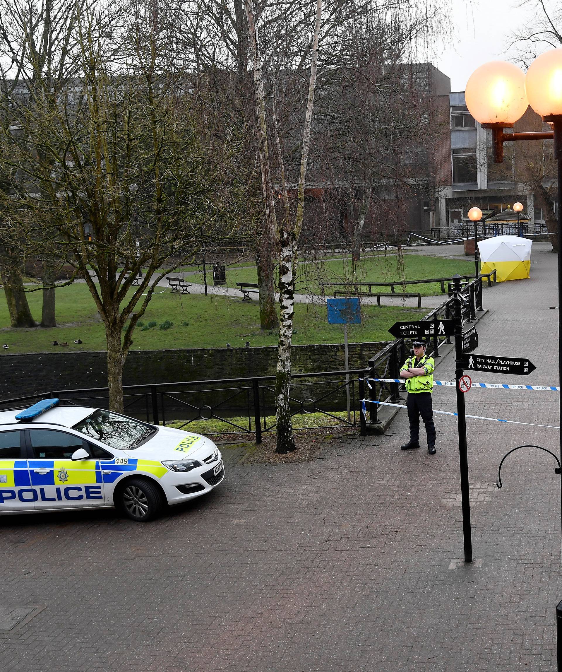 Police officers stand at crime scene tape, as a tent covers a park bench on which former Russian inteligence officer Sergei Skripal, and a woman were found unconscious after they had been exposed to an unknown substance, in Salisbury