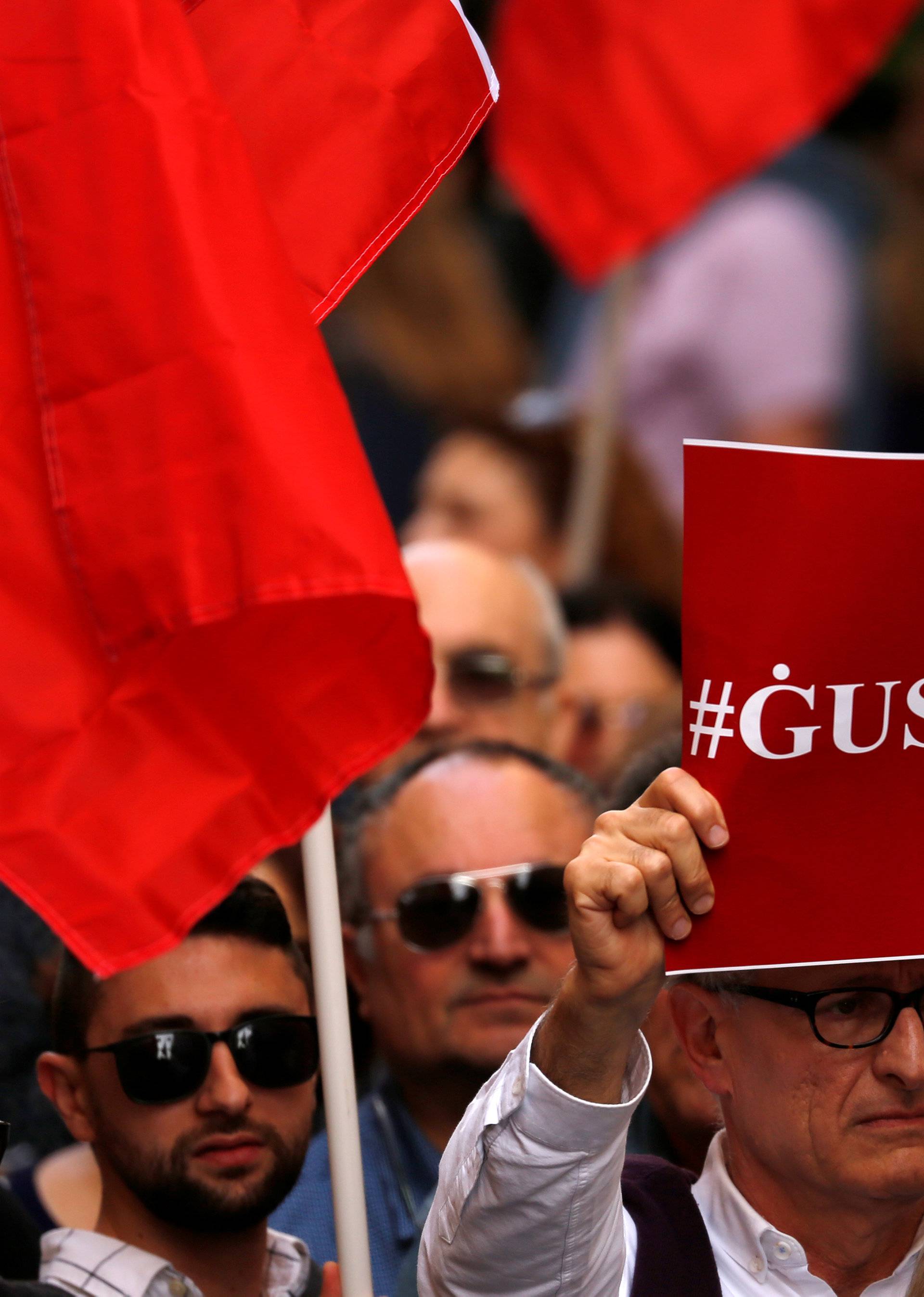 A protestor carries a placard reading "Justice" during a protest against government corruption revealed by the Daphne Project, in Valletta