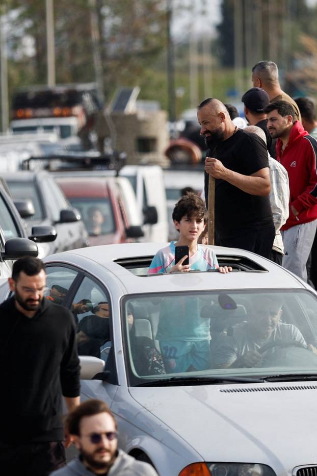 Displaced people cross the bridge linking southern Lebanon to the rest of the country, which was hit earlier in an Israeli strike, in Qasmiyeh