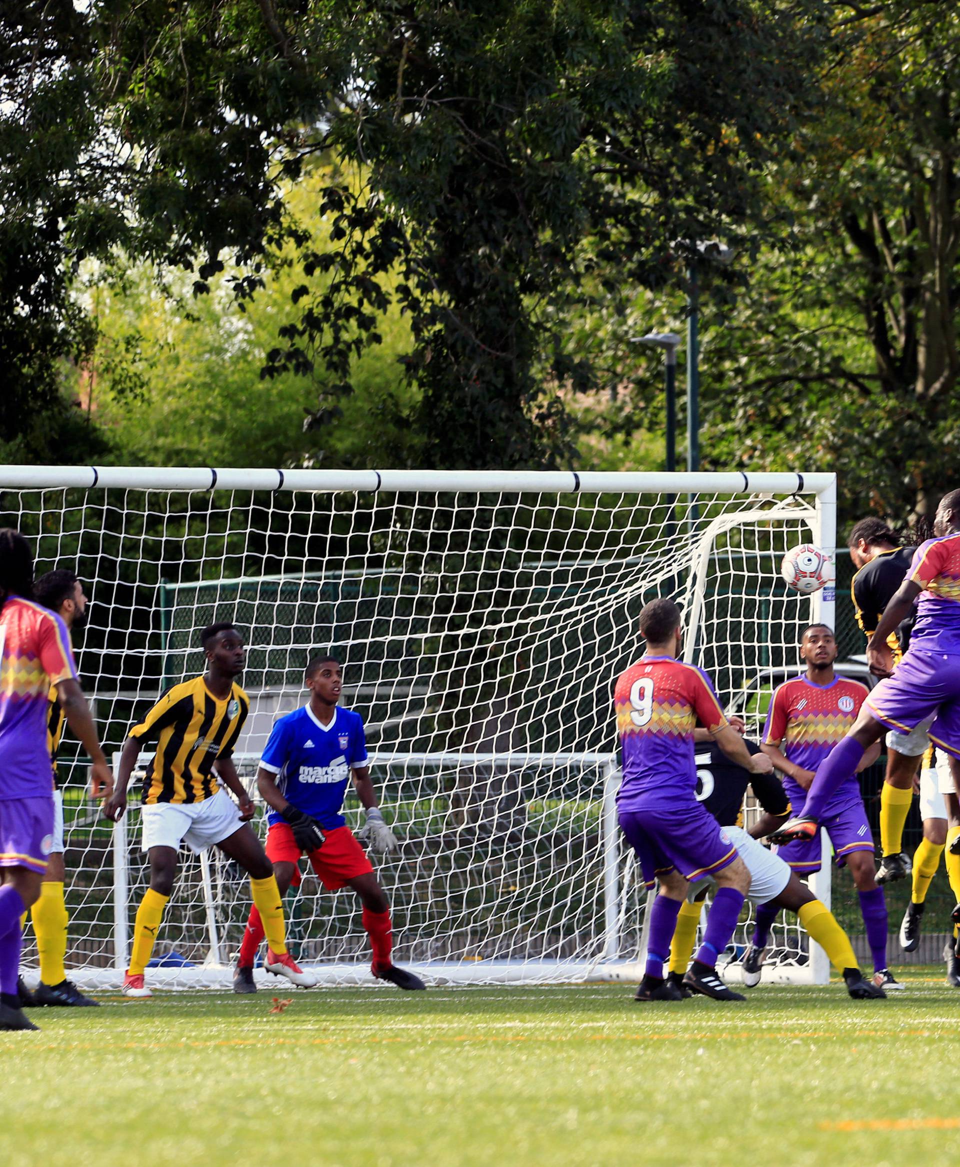 Clapton CFC players (blue jersey) attack the defence of Ealing Town during away game in East Acton, in London