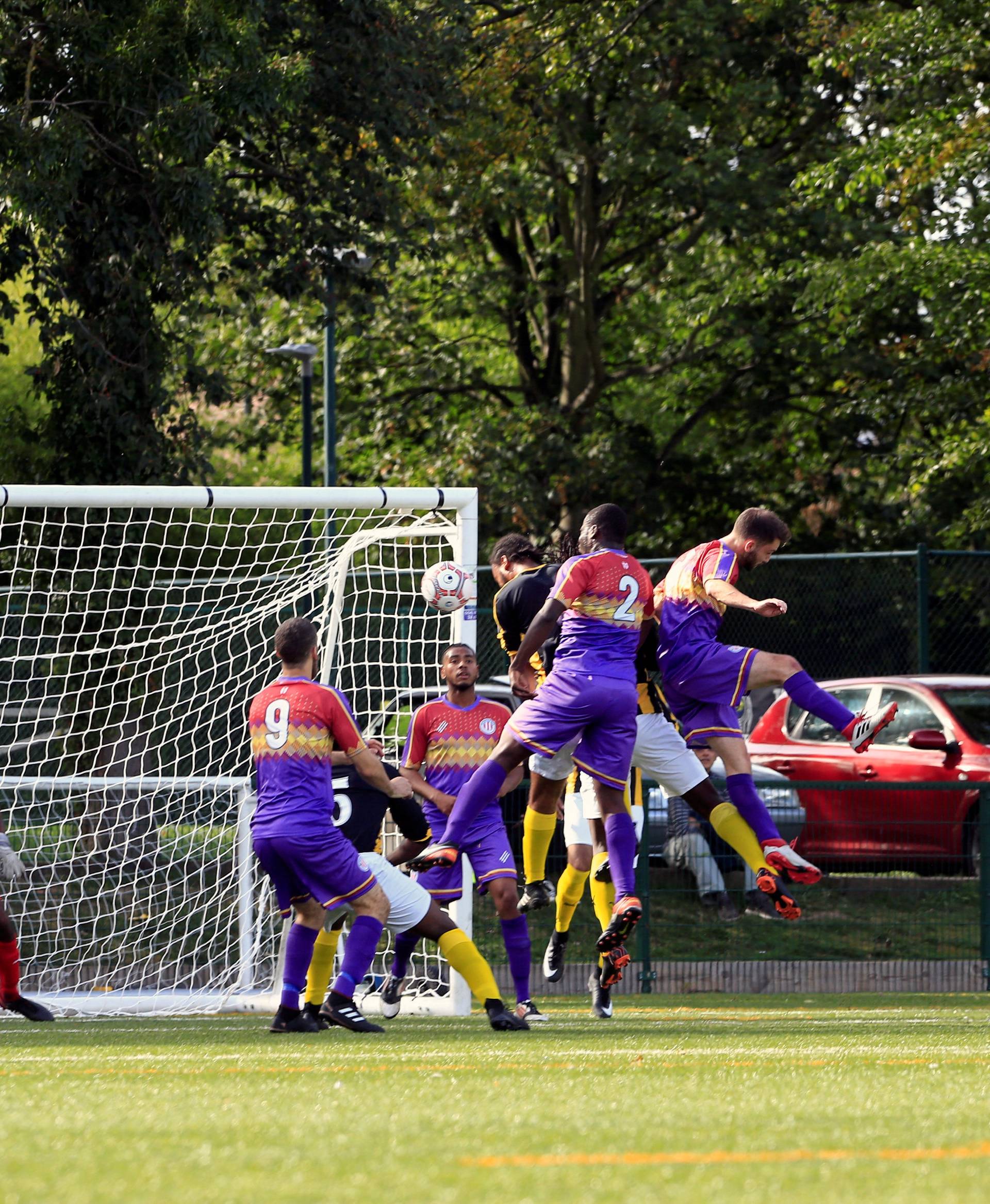 Clapton CFC players (blue jersey) attack the defence of Ealing Town during away game in East Acton, in London