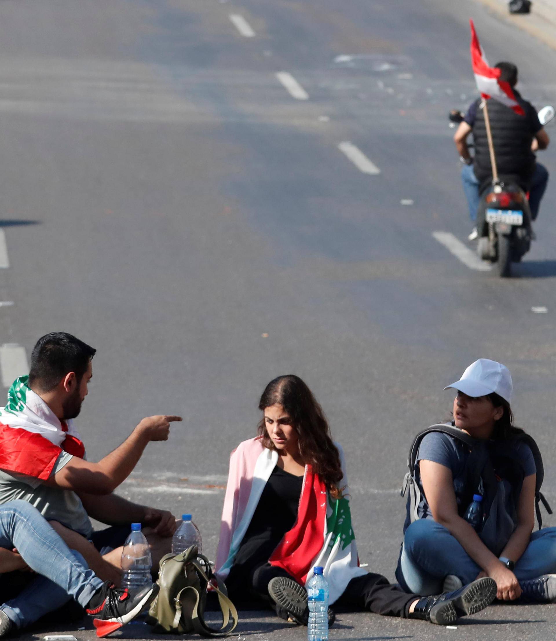 Protesters sit on the road during a road block in Beirut