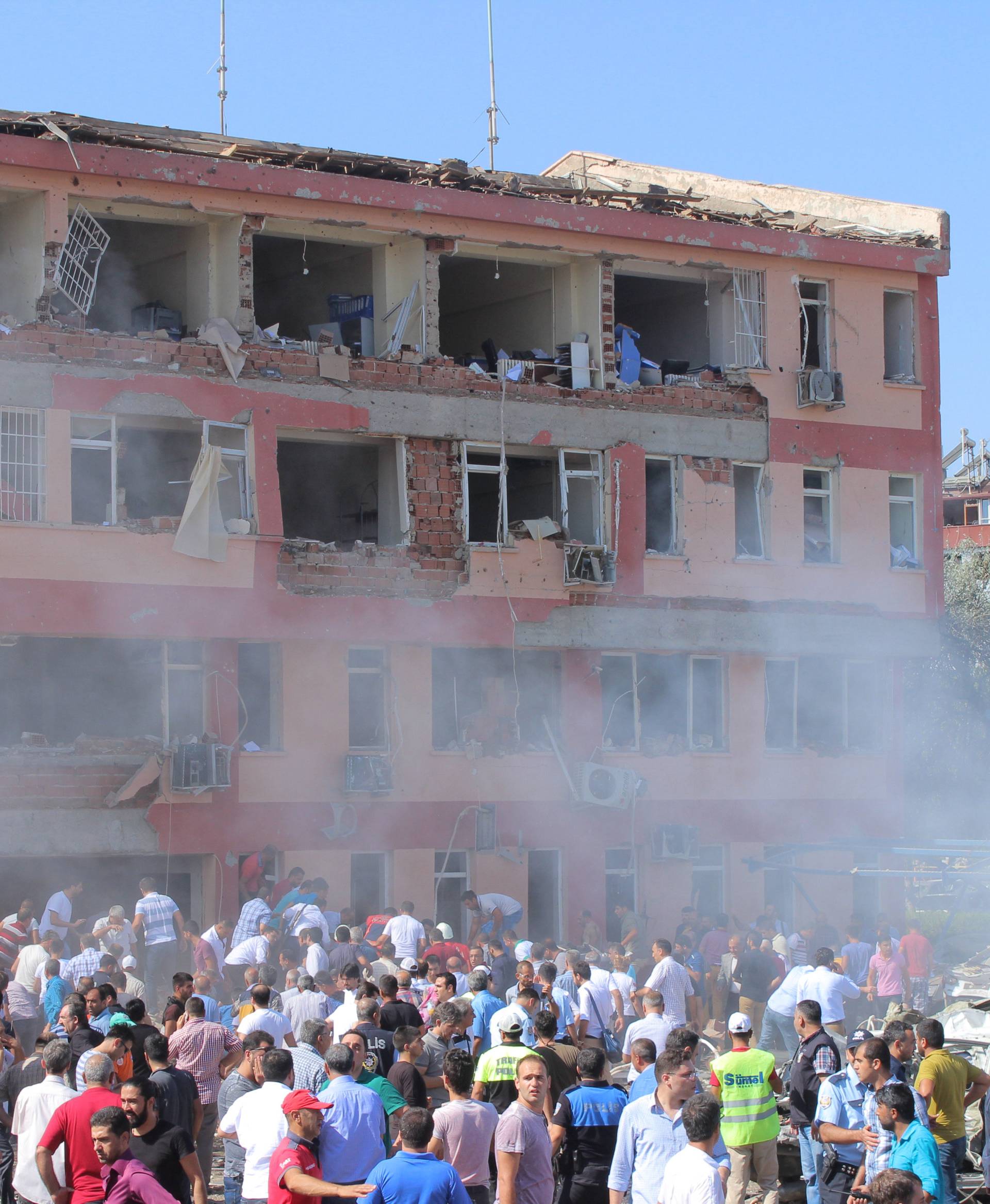 People rush to the blast scene after a car bomb attack on a police station in the eastern Turkish city of Elazig