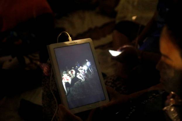 A family member looks at a photo near Tham Luang cave complex, as members of under-16 soccer team and their coach have been found alive according to a local media