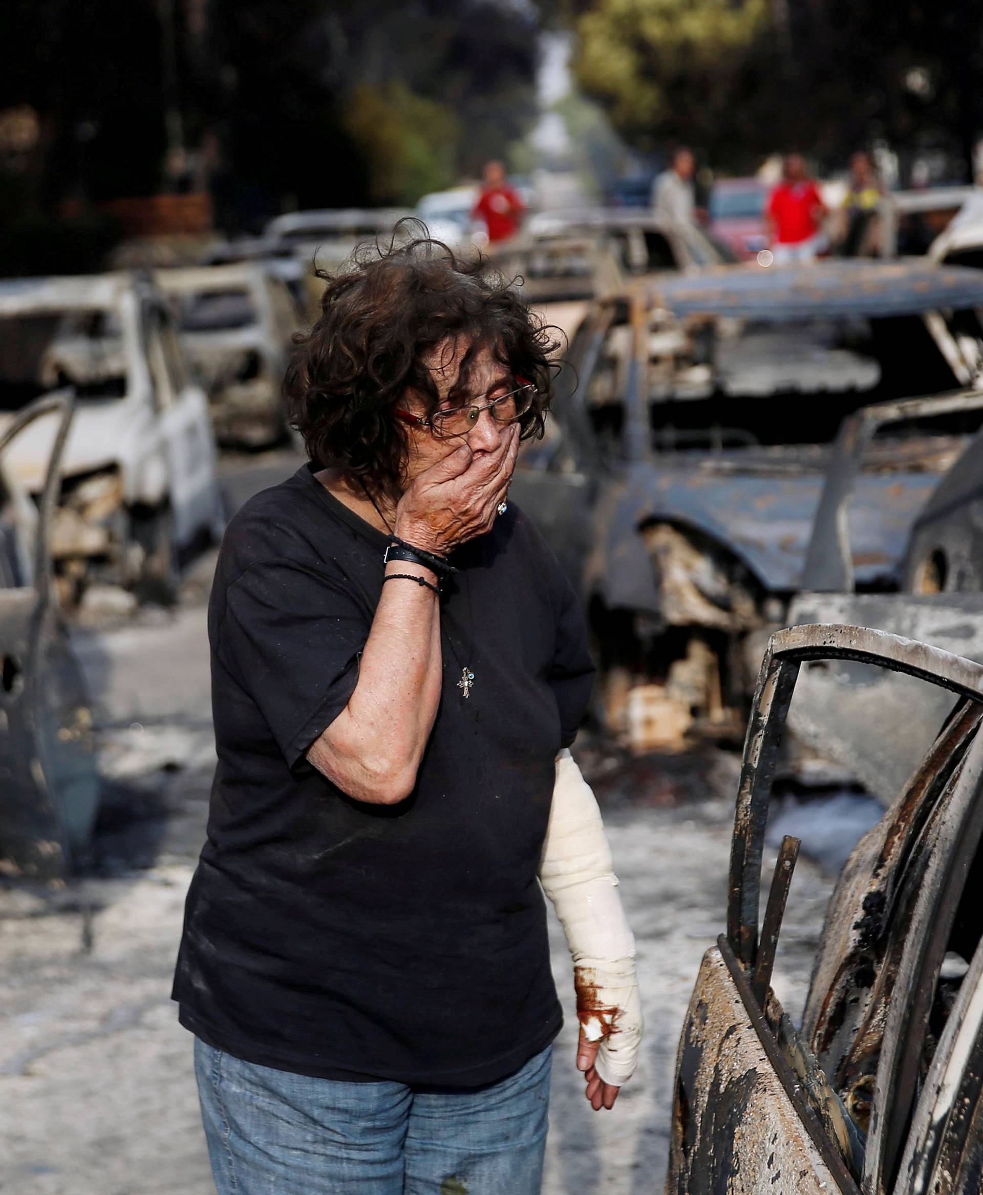 A woman reacts as she tries to find her dog, following a wildfire at the village of Mati, near Athens