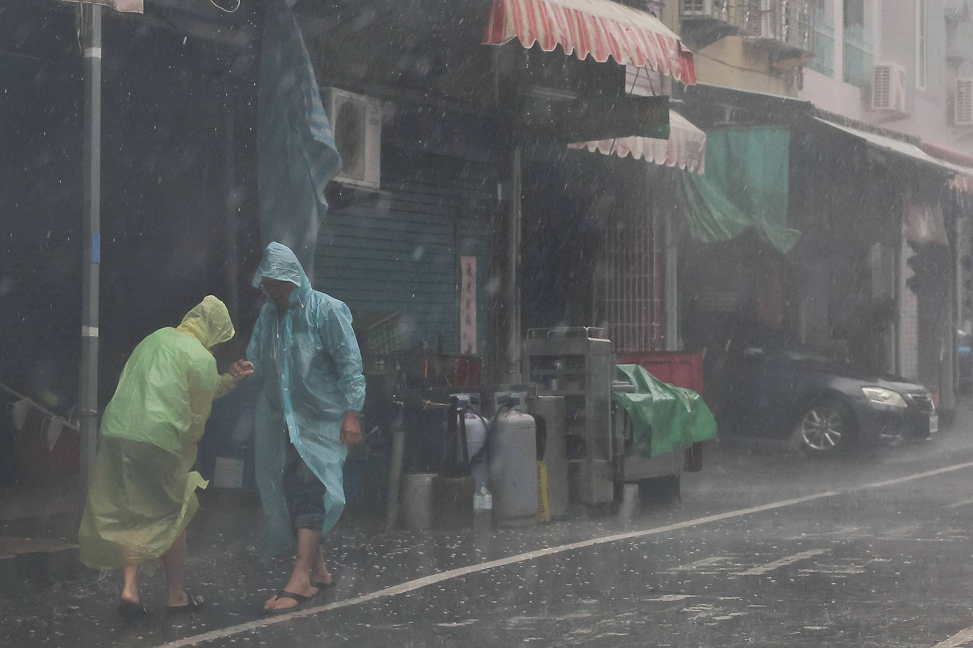 Two people help each other walk as Typhoon Krathon approaches, in Kaohsiung