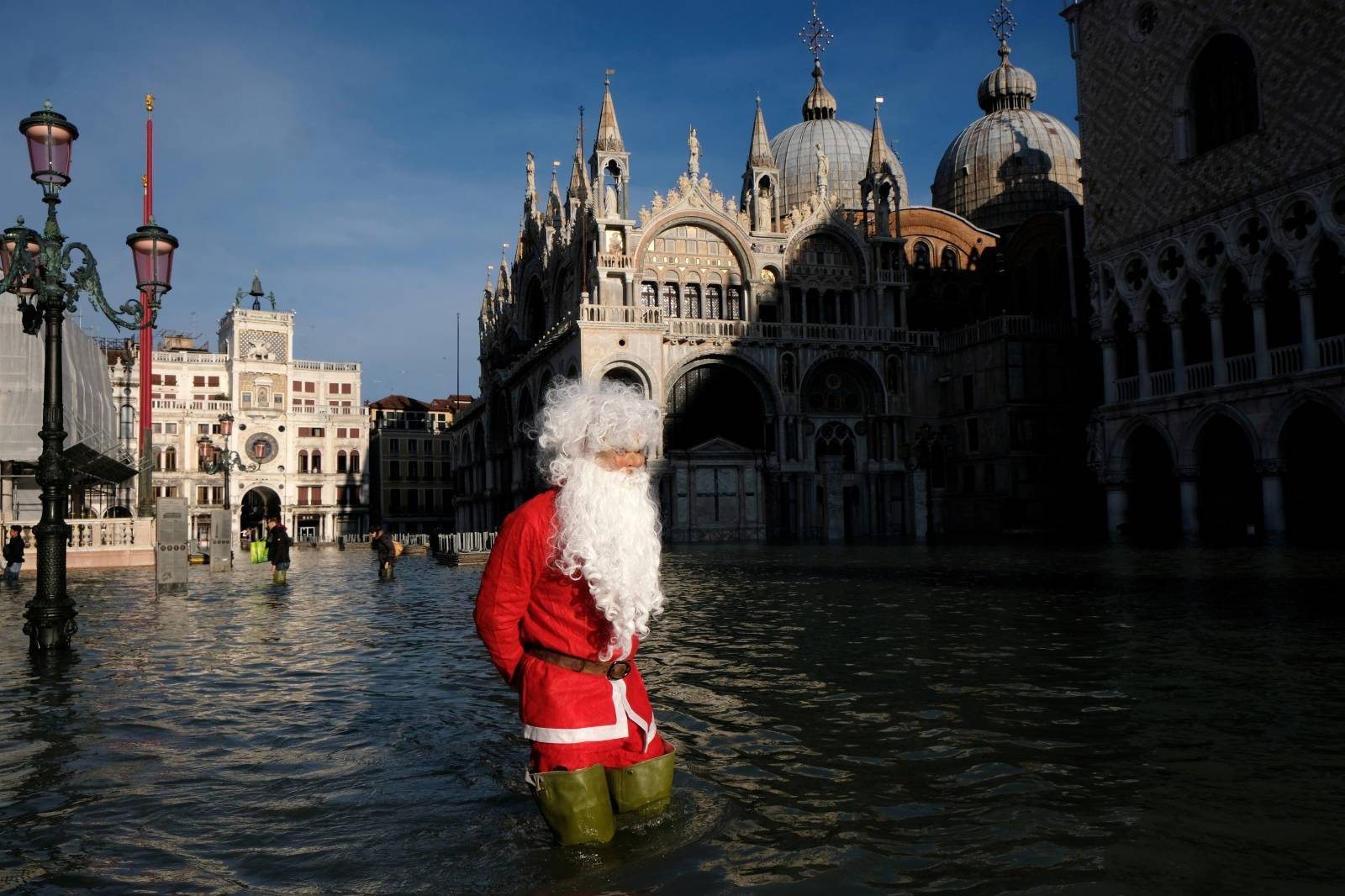 A man dressed as Santa Claus wades through floodwater in St. Mark's Square during high tide in Venice