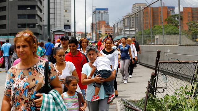 People line up expecting to buy food outside a supermarket in Caracas