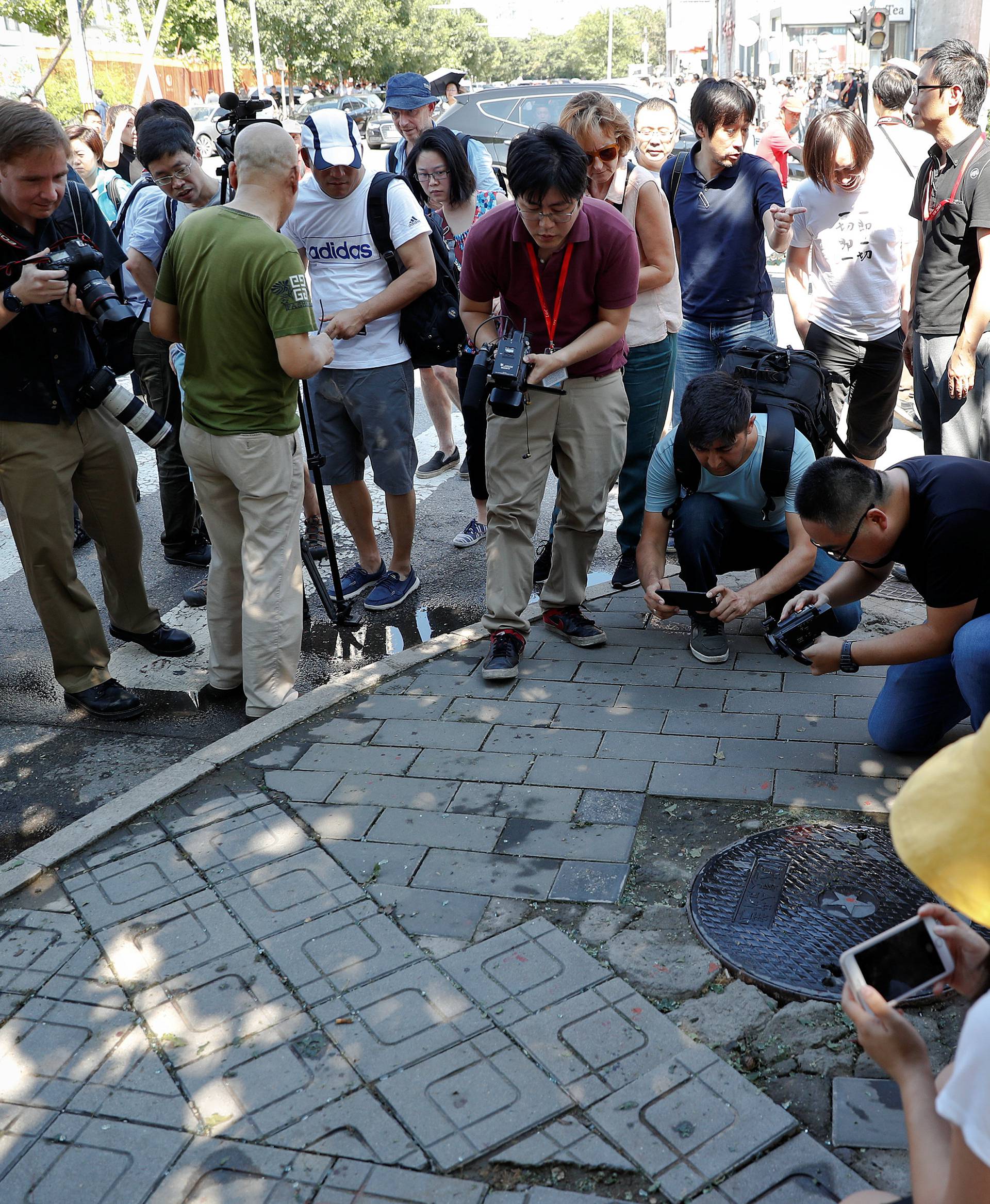 Reporters take pictures at the site of a blast outside the U.S. embassy in Beijing