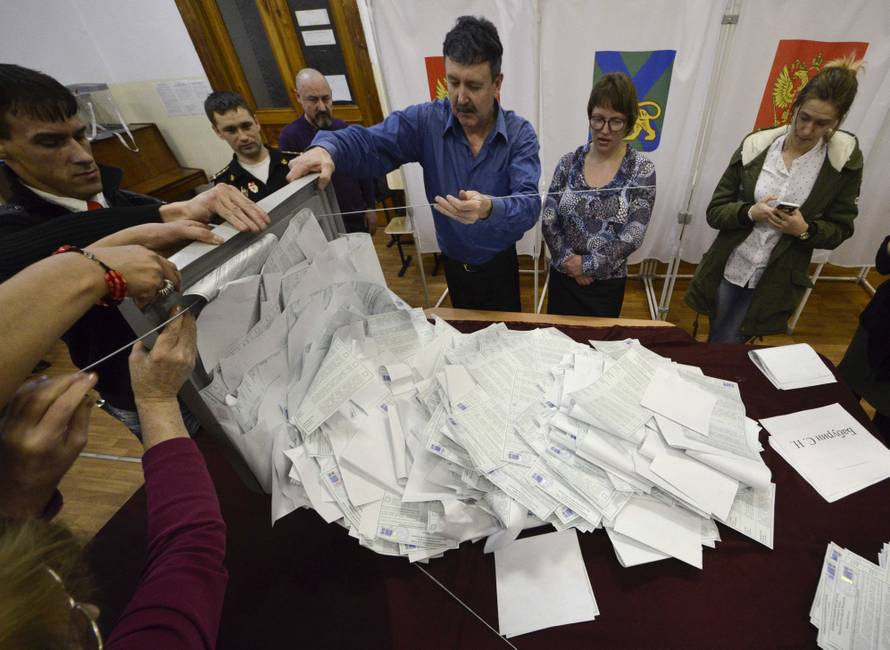 Members of a local election commission empty a ballot box before starting to count votes during the presidential election in Vladivostok