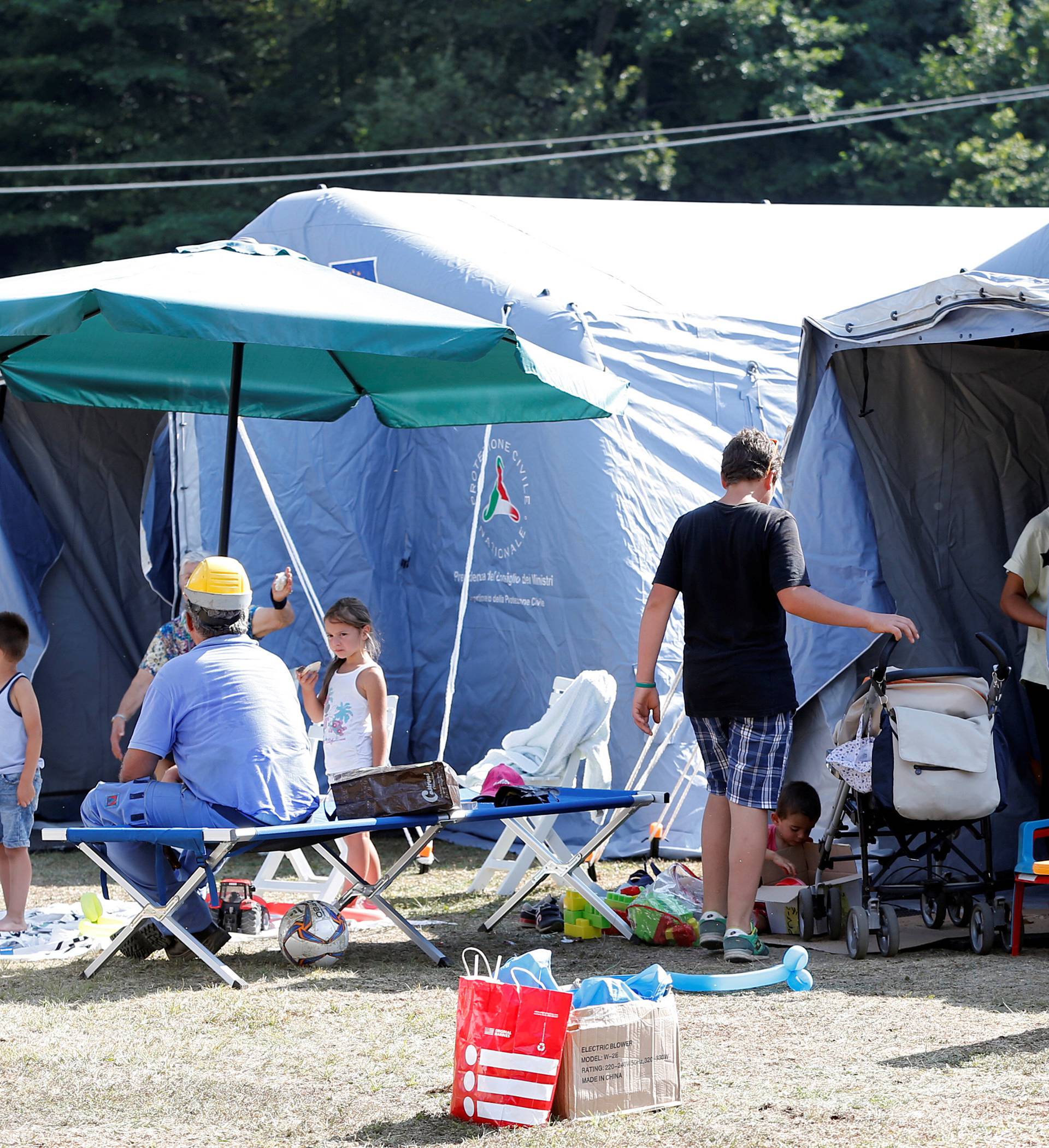 Survivors stand outside a tent camp set up as temporary shelter following an earthquake in Amatrice