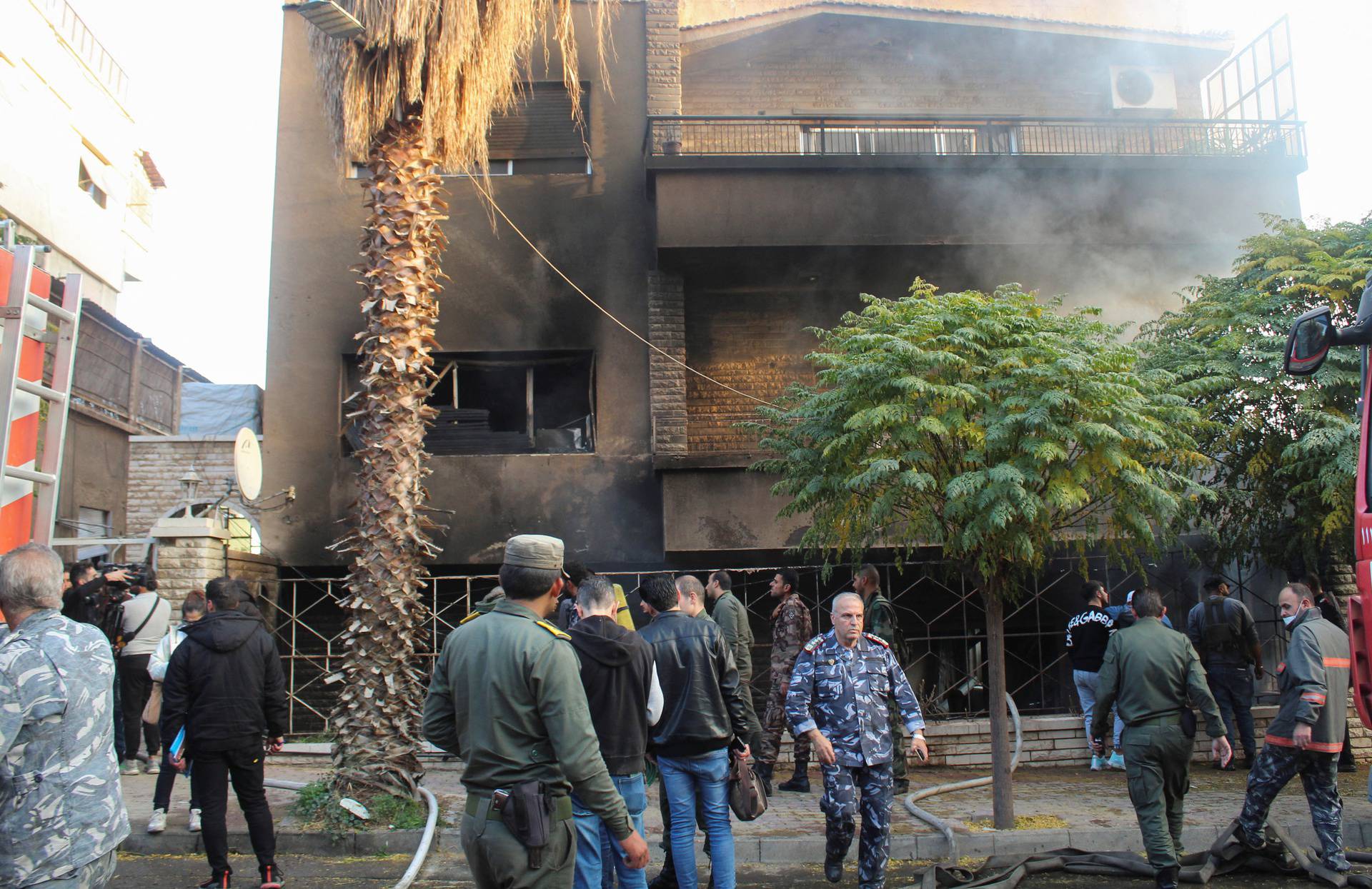 People walk near a damaged site after what Syrian state news agency said was an Israeli strike in Damascus suburb of Mazzeh