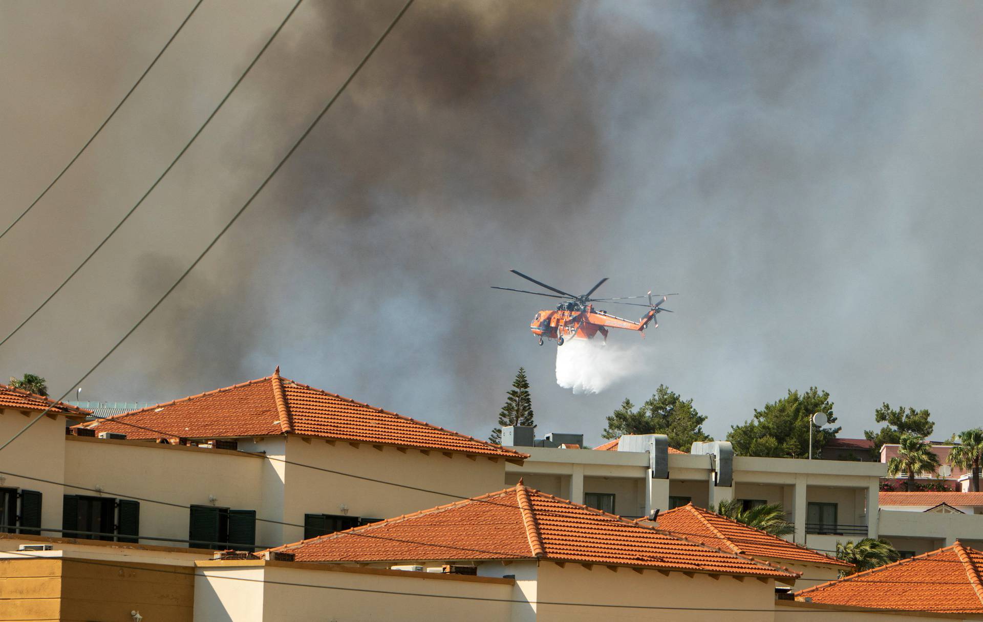 A firefighting helicopter drops water over a wildfire burning near Lindos, on the island of Rhodes