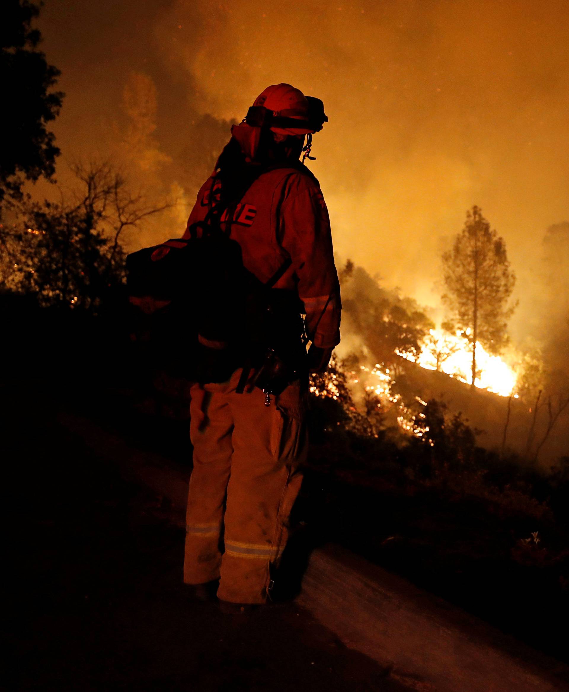 A firefighter watches the flames of the Carr Fire advance as it burns west of Redding