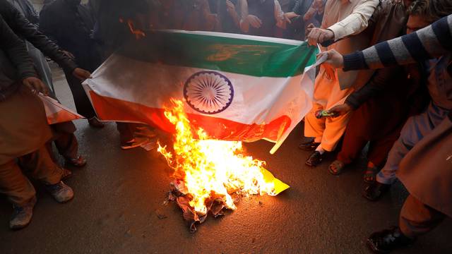 People burn a poster depicting India's flag against what they call airspace violation by the Indian military aircrafts, in a protest in Peshawar