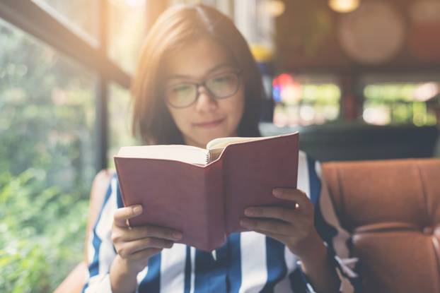 Focus on book. Relaxed Asian Woman reading a book. Happiness, co